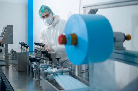 Workers producing surgical mask in modern factory, Covid-19 protection and medical concept.