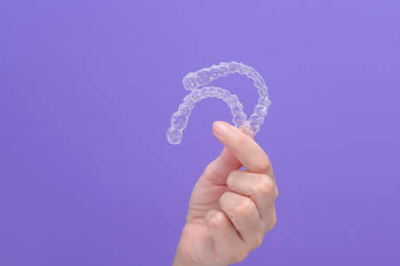 close up of woman's hand holding invisalign braces in studio, dental healthcare and Orthodontic concept.の写真素材