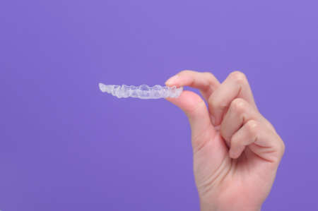 close up of woman's hand holding invisalign braces in studio, dental healthcare and Orthodontic concept.の写真素材