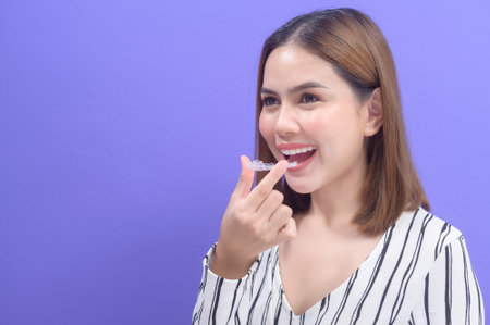 A young smiling woman holding invisalign braces in studio, dental healthcare and Orthodontic...