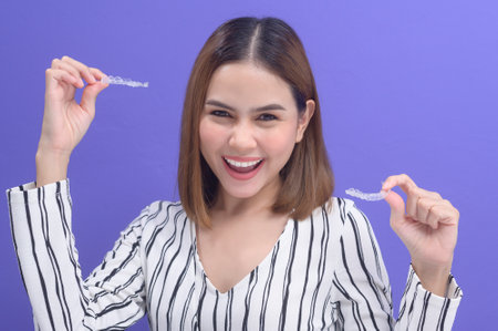 A young smiling woman holding invisalign braces in studio, dental healthcare and Orthodontic...