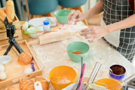 A Beautiful asian woman is making bakery ,   live streaming or recording video on social media in her houseの写真素材