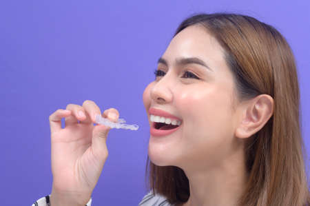 A young smiling woman holding invisalign braces in studio, dental healthcare and Orthodontic concept.の写真素材
