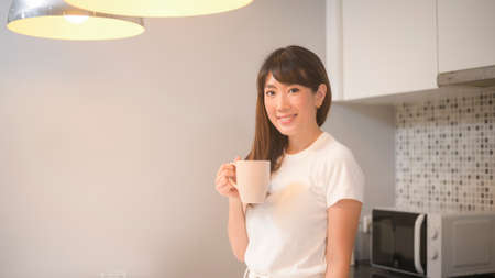 A portrait of young beautiful woman drinking glass of water in kitchen