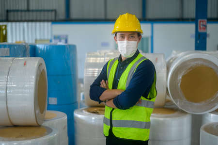 An engineering man wearing medical mask , protective helmet working in warehouse factoryの写真素材