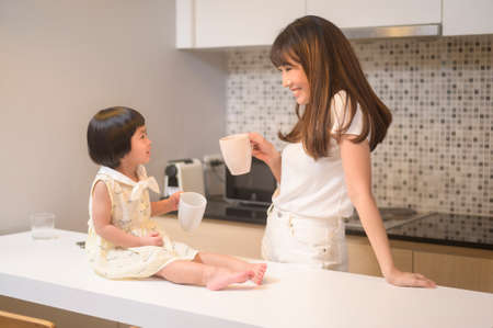A portrait of happy mom and daughter in kitchen at home