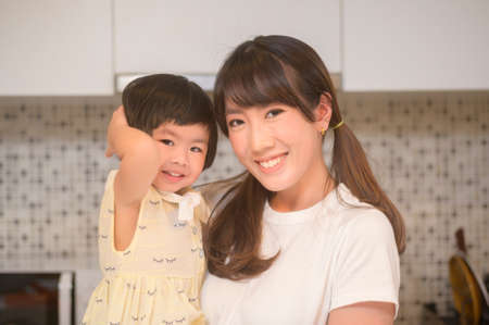 A portrait of happy mom and daughter in kitchen at homeの写真素材