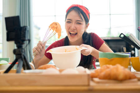 A Beautiful asian woman is making bakery ,   live streaming or recording video on social media in her houseの写真素材