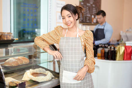 A beautiful woman bakery or coffee shop owner is smiling in her shopの写真素材