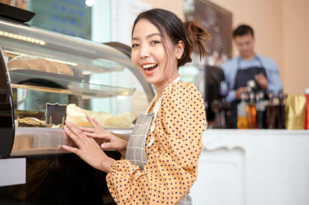 A beautiful woman bakery or coffee shop owner is smiling in her shopの写真素材