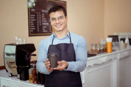 Baristas hand taking cup of hot coffee and bakery to offering to customer  in coffee shopの写真素材