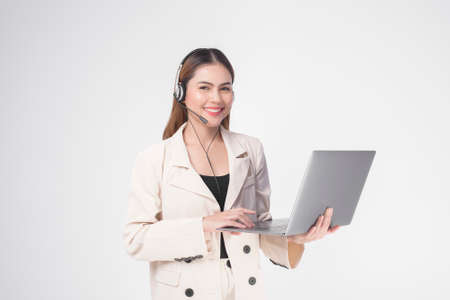 Customer service operator woman in suit wearing headset over white background studioの写真素材