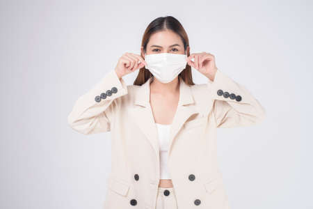 portrait of young businesswoman wearing a surgical mask over white background studioの写真素材