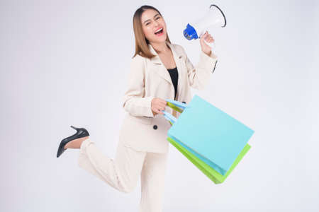Young beautiful woman in suit holding colorful shopping bags over white background studioの写真素材