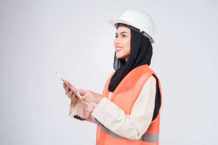 A muslim woman engineer wearinng a protective helmet over white backgroud studioの写真素材