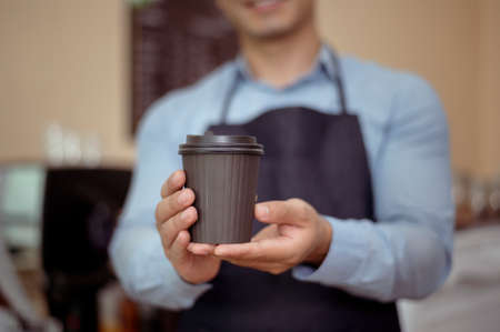 Baristas hand taking cup of hot coffee and bakery to offering to customer  in coffee shopの写真素材