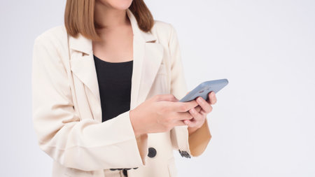 Portrait of young beautiful woman in suit using smart phone over white backgroundの写真素材