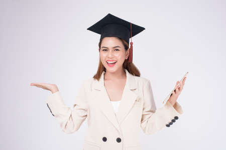 Portrait of young woman graduated over white backgroundの写真素材