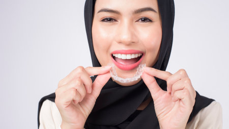 Young muslim woman holding invisalign braces in studio, dental healthcare and Orthodontic concept.の写真素材