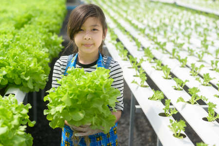 A happy cute girl learning and studying in hydroponic greenhouse farm, education and scientist conceptの写真素材