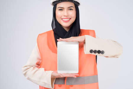 A muslim woman engineer wearinng a protective helmet over white backgroud studioの写真素材