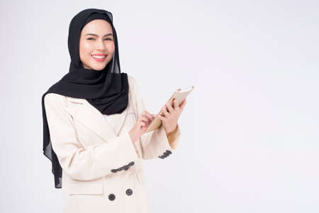 Young beautiful muslim businesswoman in suit holding tablet over white Studio backgroundの写真素材