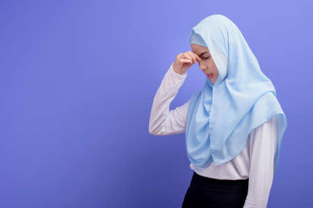 A young muslim woman wearing hijab stressed and tired over blue background studio.の写真素材