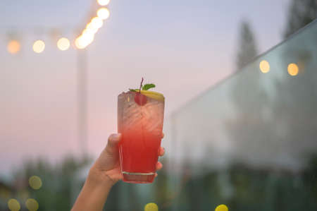 Close up human hand holding a glass of alcohol beverage in restaurant