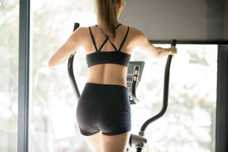 A beautiful woman using an elliptic trainer at gym, concept of healthy lifestyle, sports, training,...
