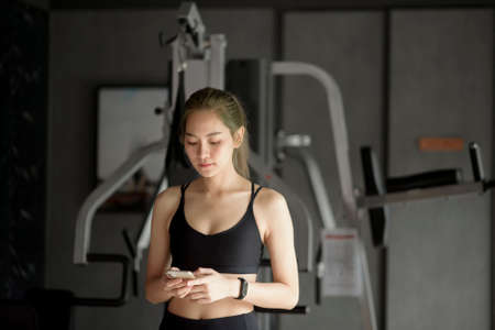 A beautiful smiling woman using a phone while in a gym, Fitness and technology concept .の写真素材