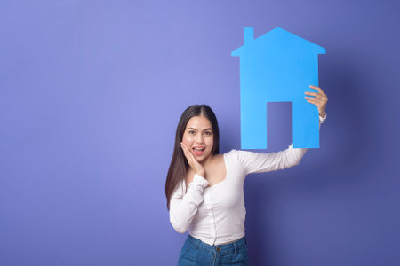 Portrait of beautiful woman  is holding blue  home on purple backgroundの写真素材