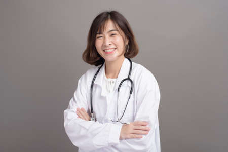 A portrait of young confident woman doctor isolated over grey background studioの写真素材
