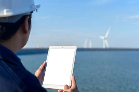 a man engineer is wearing a protective helmet on her head, using tablet Analytics engineering data.の写真素材