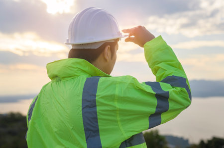 a man engineer is putting a protective helmet on her head at sunset.の写真素材