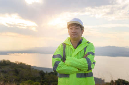 a man engineer is putting a protective helmet on her head at sunset.の写真素材