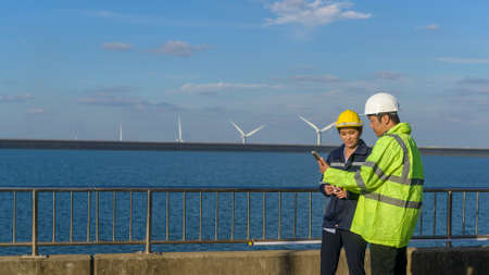 people engineer are wearing a protective helmet on head, using tablet Analytics engineering data.