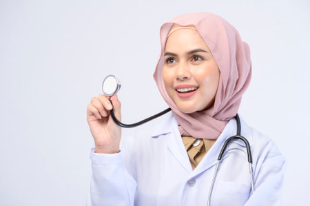 A female muslim doctor with hijab over white background studio.の写真素材
