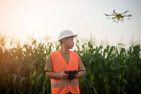 A male engineer controlling drone spraying fertilizer and pesticide over farmland,High technology innovations and smart farmingの写真素材