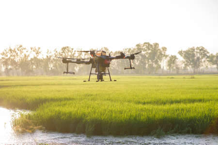 Agriculture drone flying and spraying fertilizer and pesticide over farmland,High technology innovations and smart farmingの写真素材