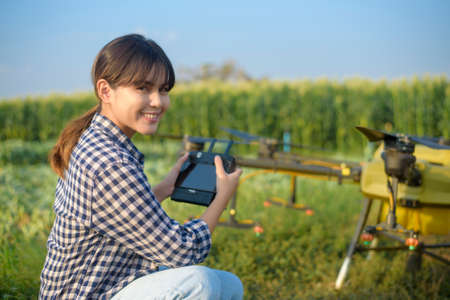 A young smart farmer controlling drone spraying fertilizer and pesticide over farmland,High technology innovations and smart farmingの写真素材