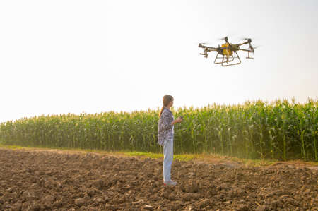 A young smart farmer controlling drone spraying fertilizer and pesticide over farmland,High technology innovations and smart farmingの写真素材