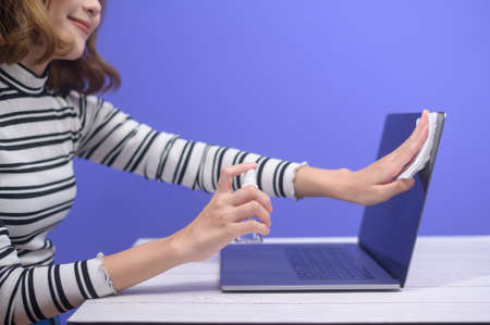 young woman sanitizing alcohol spray with computer , covid-19 protection concept .の写真素材