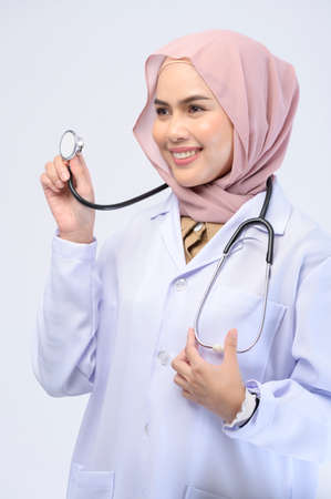 A female muslim doctor with hijab over white background studio.の写真素材