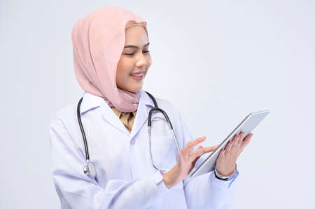 A female muslim doctor with hijab over white background studio.の写真素材