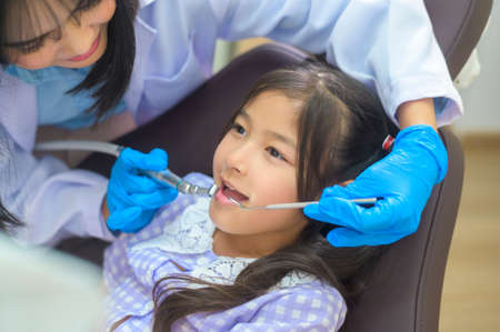 A little cute girl having teeth examined by dentist in dental clinic, teeth check-up and Healthy teeth conceptの写真素材
