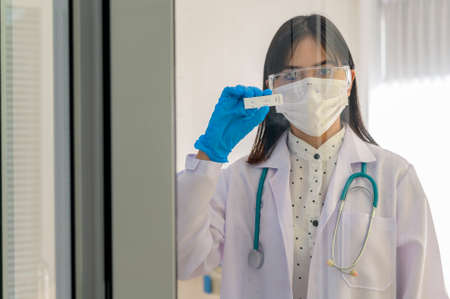 Young female doctor holding ATK kit in hospital, covid19 and pandemic concept