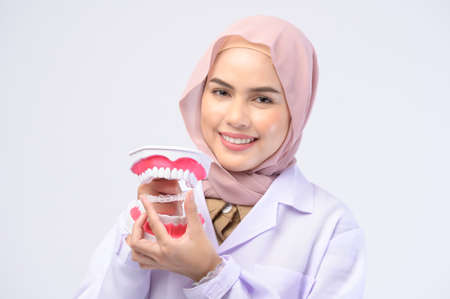 A muslim female dentist holding invisalign braces over white background studio, dental healthcare...