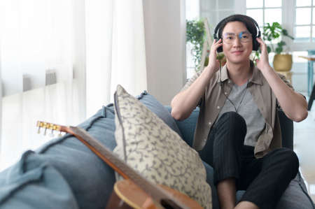 An asian man is listening Music in living room .の写真素材
