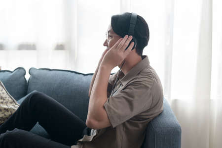 An asian man is listening Music in living room .