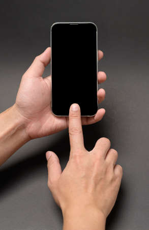 close up hand holding smart phone over black background studio
